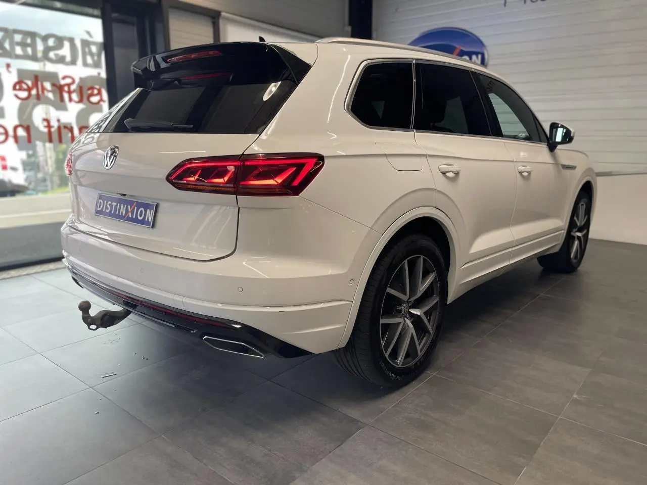 Vue 3/4 arrière droite du Volkswagen Touareg blanc avec jantes alliage 20 pouces et feux arrière LED allumés.