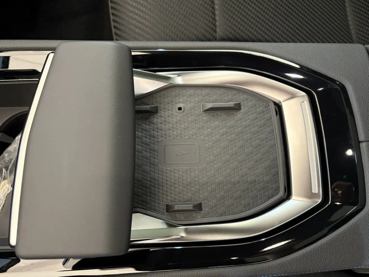 Gros plan sur la zone de recharge par induction noire et argentée dans l'habitacle du Renault Espace blanc.