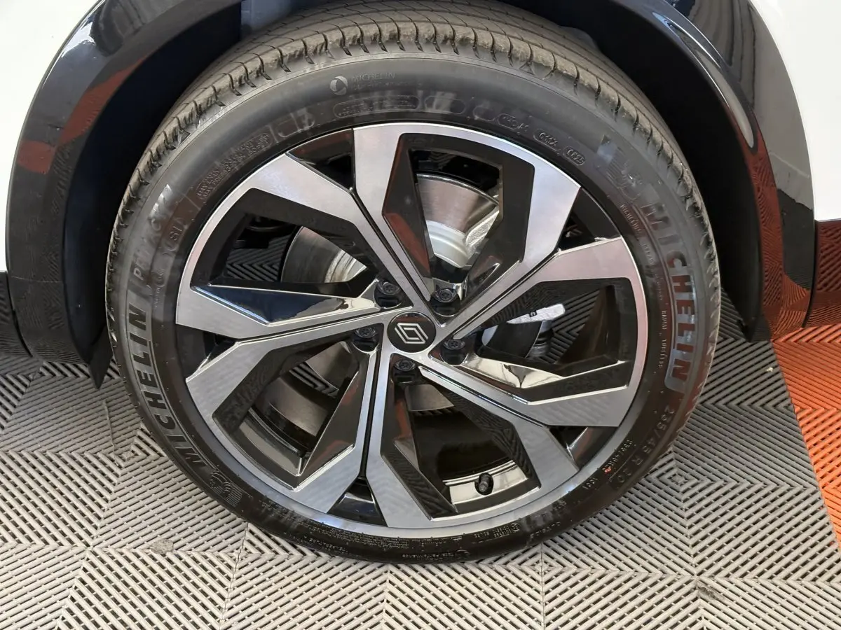 Gros plan sur la roue avant droite d’un Renault Espace blanc 2025, jante alliage noire et argent avec logo Renault central.