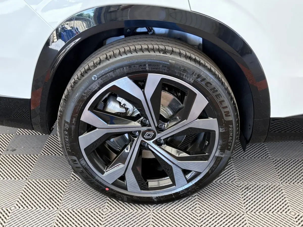 Gros plan sur la roue avant droite du Renault Espace blanc, jante alliage moderne bicolore et pneu Michelin.