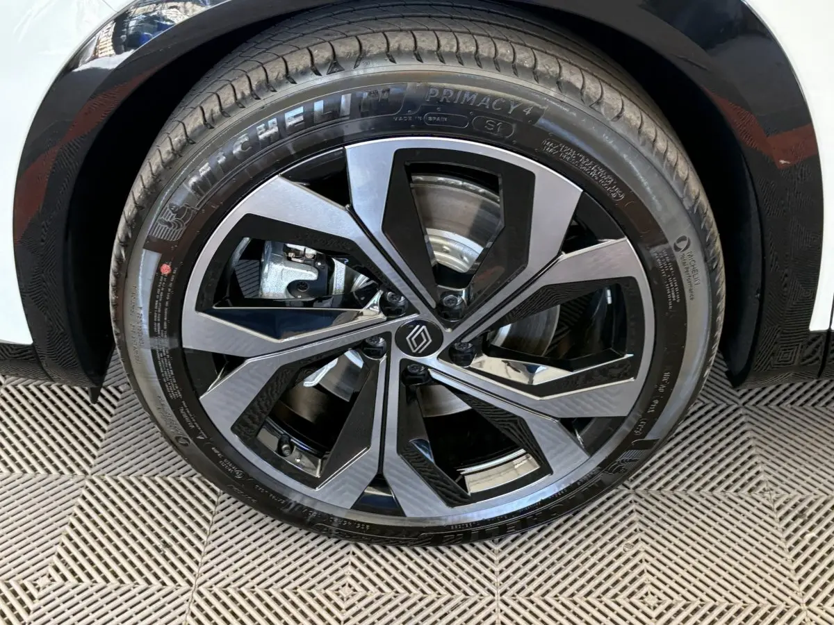 Gros plan sur la roue avant droite de la Renault Espace blanche, jante alliage noire et argentée au design moderne.