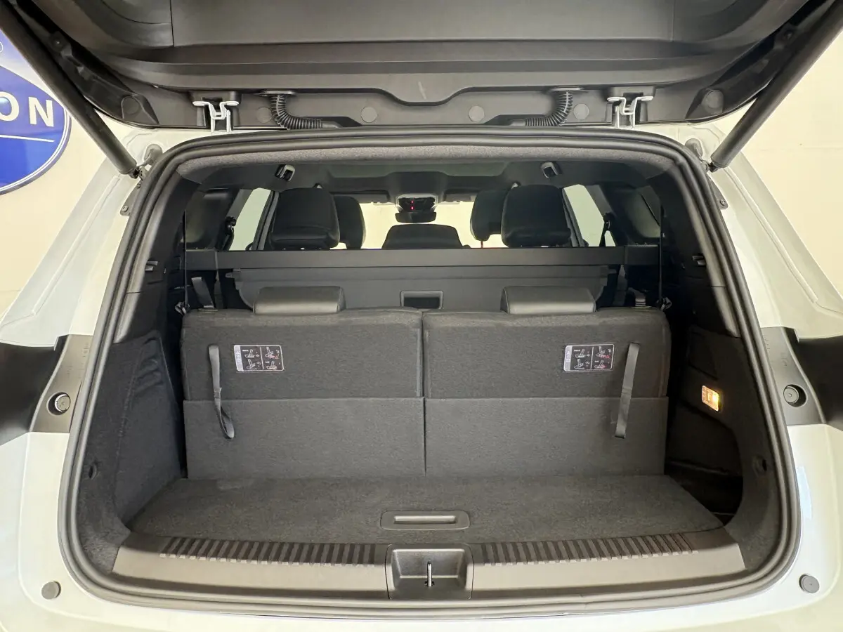 Coffre ouvert vu de l'arrière d'un Renault Espace blanc avec sièges arrière relevés et habillage intérieur noir.