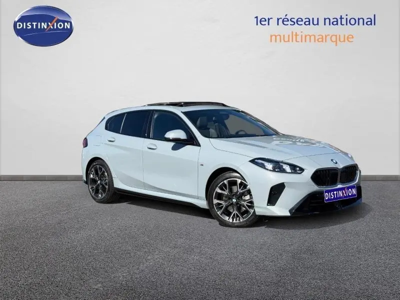 BMW Série 1 120dA M Sport vue 3/4 avant en blanc Alpinweiss avec jantes alu noires sur fond neutre.