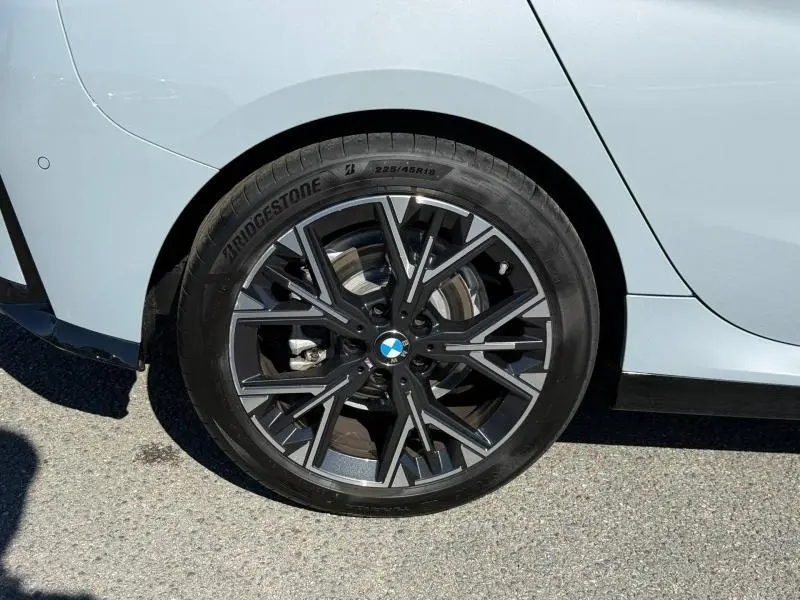 Gros plan sur la roue arrière droite d’une BMW Série 1 120dA M Sport en M Brooklyn Grey métallisé avec jante alu noire à design complexe.