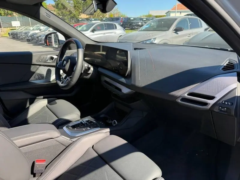 Vue intérieure côté conducteur de la BMW Série 1 120dA M Sport 2025 avec tableau de bord moderne et sièges sport noirs.