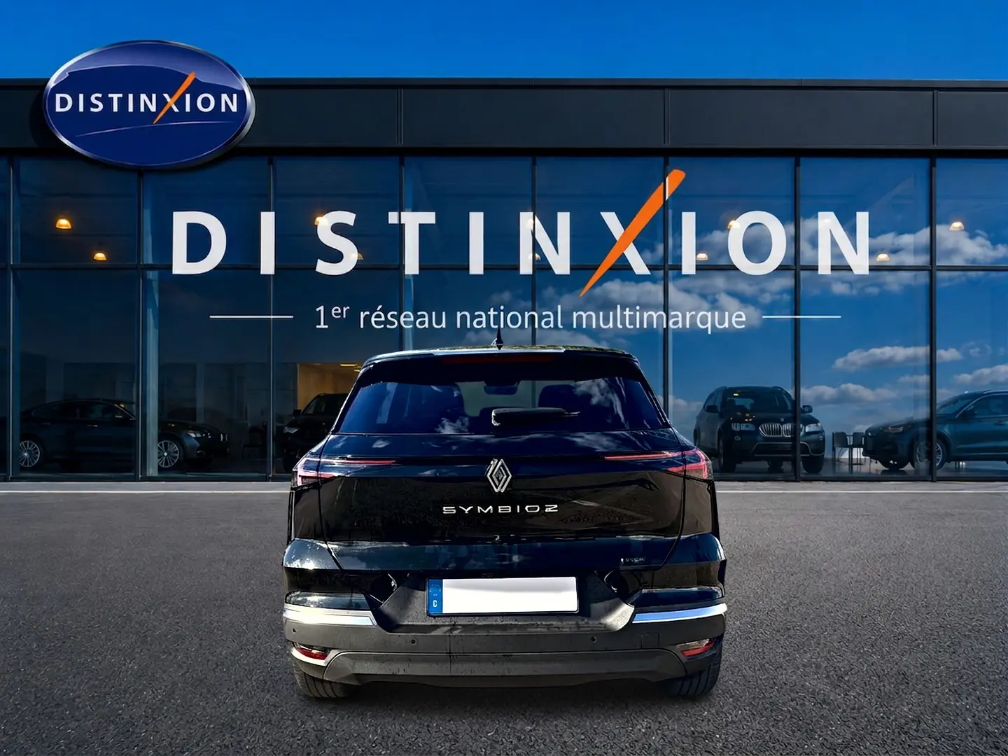Vue arrière d'un Renault Symbioz noir étoile 2026, avec feux arrière LED et logo centré sur un parking devant un showroom Distinxion.