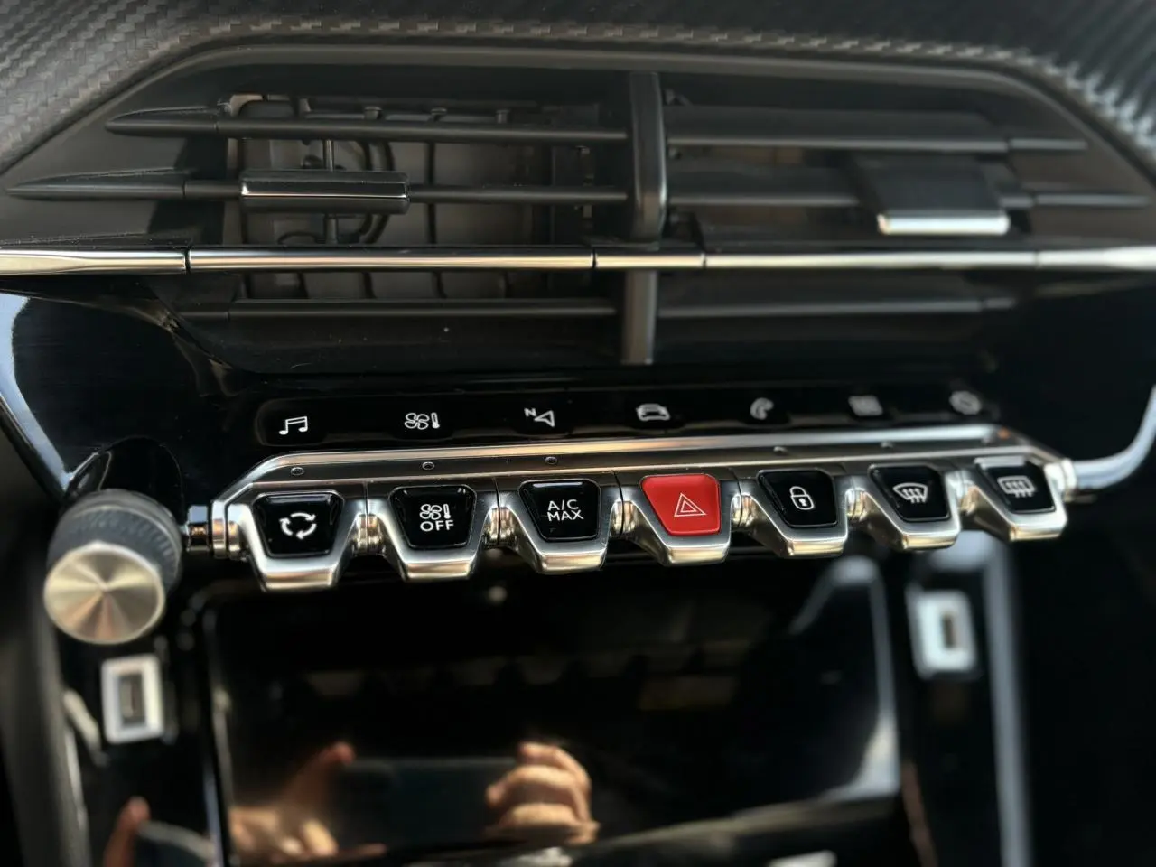 Gros plan sur la console centrale noire du Peugeot 2008 GT 2021, mettant en valeur les commandes chromées et un bouton rouge d’alerte.