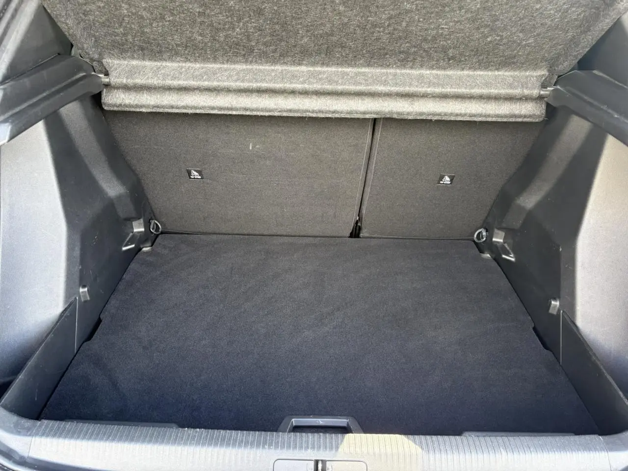Coffre ouvert vu de face, intérieur noir avec tapis de sol et banquette arrière rabattable du Peugeot 2008 Noir Onyx.