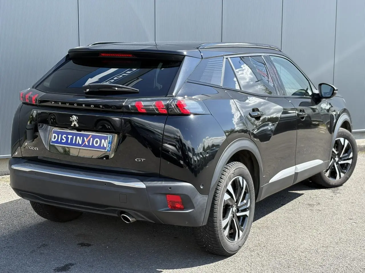 Vue 3/4 arrière droite d’un Peugeot 2008 GT noir Onyx avec feux arrière LED en forme de griffes et jantes alliage bi-ton.