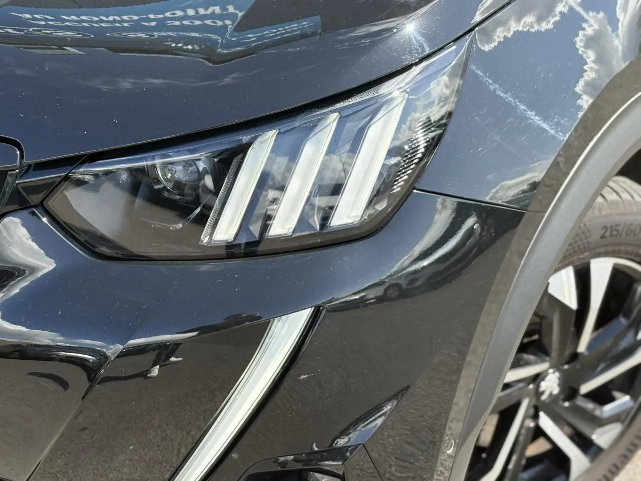 Gros plan sur le phare avant droit et la jante alliage 17'' noir Onyx du Peugeot 2008 GT noir métallisé.