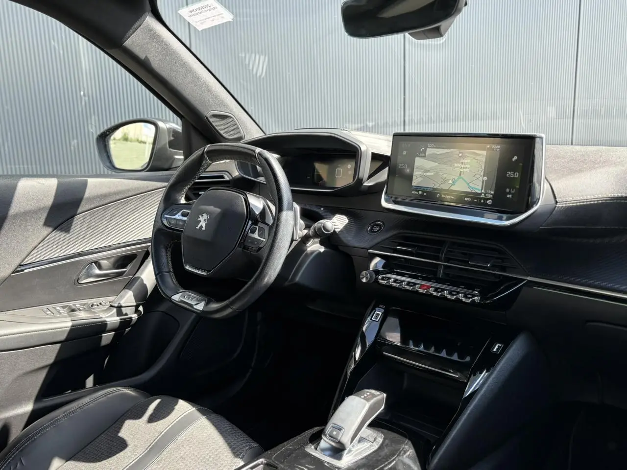 Vue intérieure côté conducteur du Peugeot 2008 noir Onyx, mettant en valeur le volant compact, l'écran tactile GPS et la console centrale moderne.