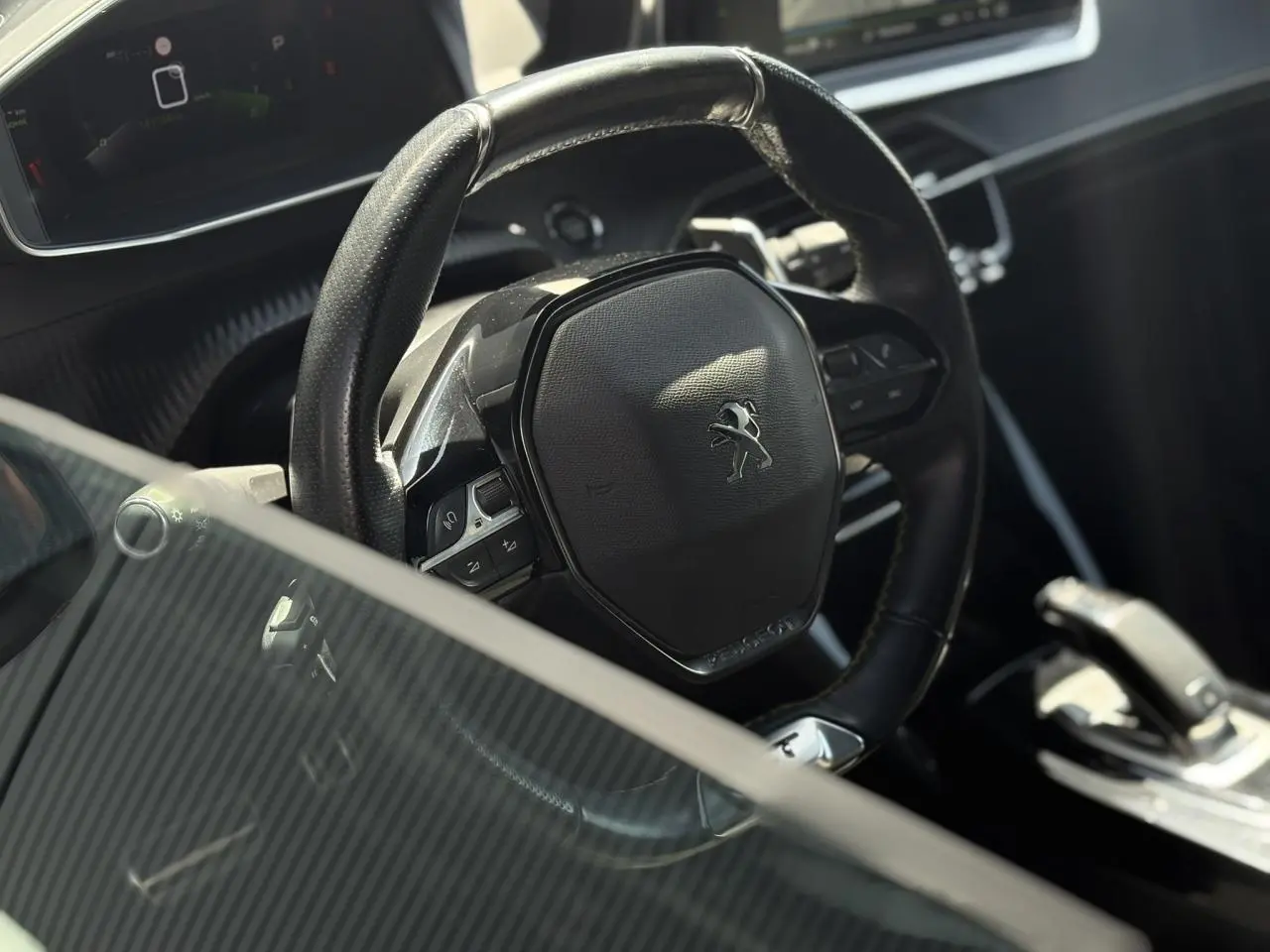 Vue rapprochée du volant cuir noir du Peugeot 2008 GT 2021 avec commandes intégrées et console de boîte automatique.