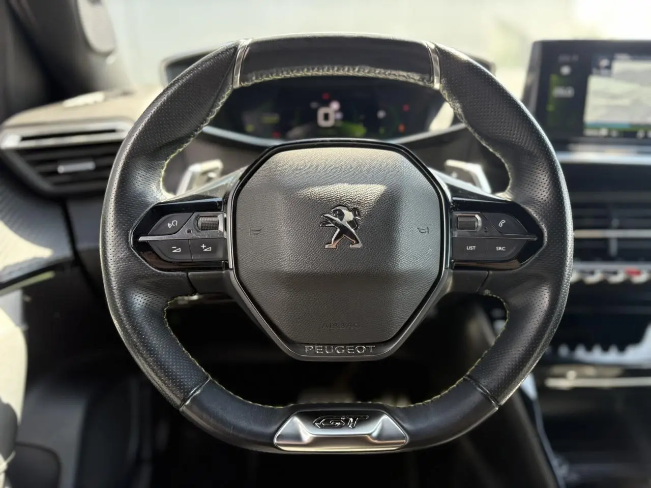 Volant cuir noir Peugeot 2008 GT vu de face avec commandes intégrées et badge GT chromé en bas.