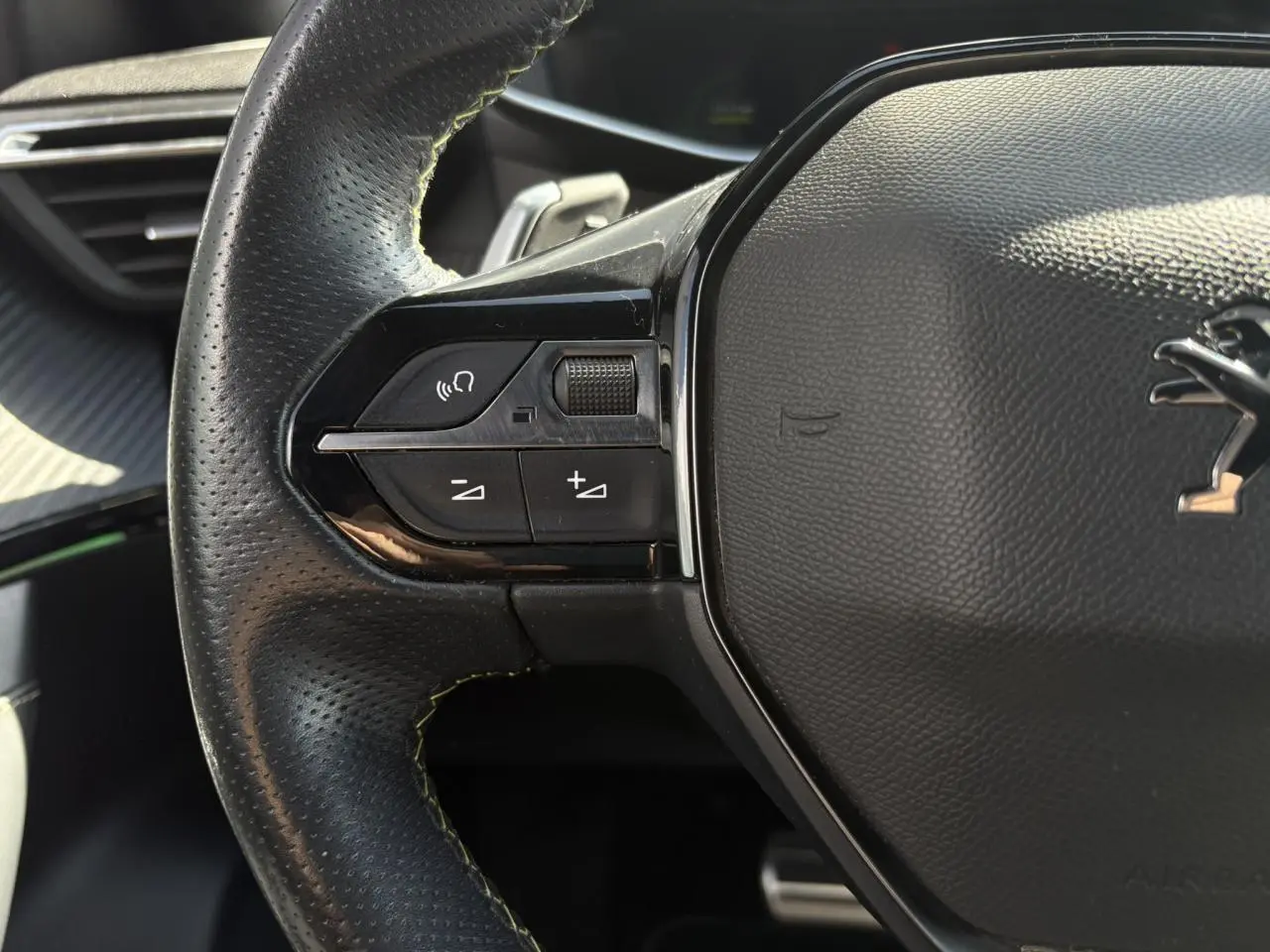 Gros plan sur la partie gauche du volant cuir noir perforé avec surpiqûres vertes du Peugeot 2008 GT 2021.