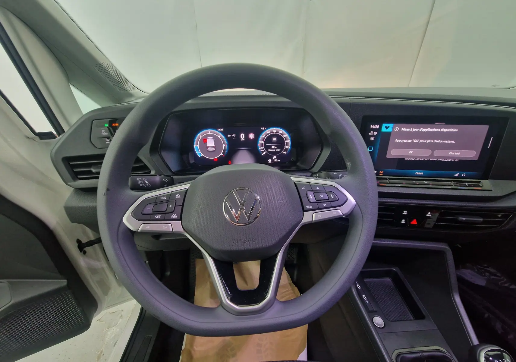 Vue intérieure côté conducteur du Volkswagen Caddy Maxi blanc, montrant les sièges avant et le tableau de bord moderne.