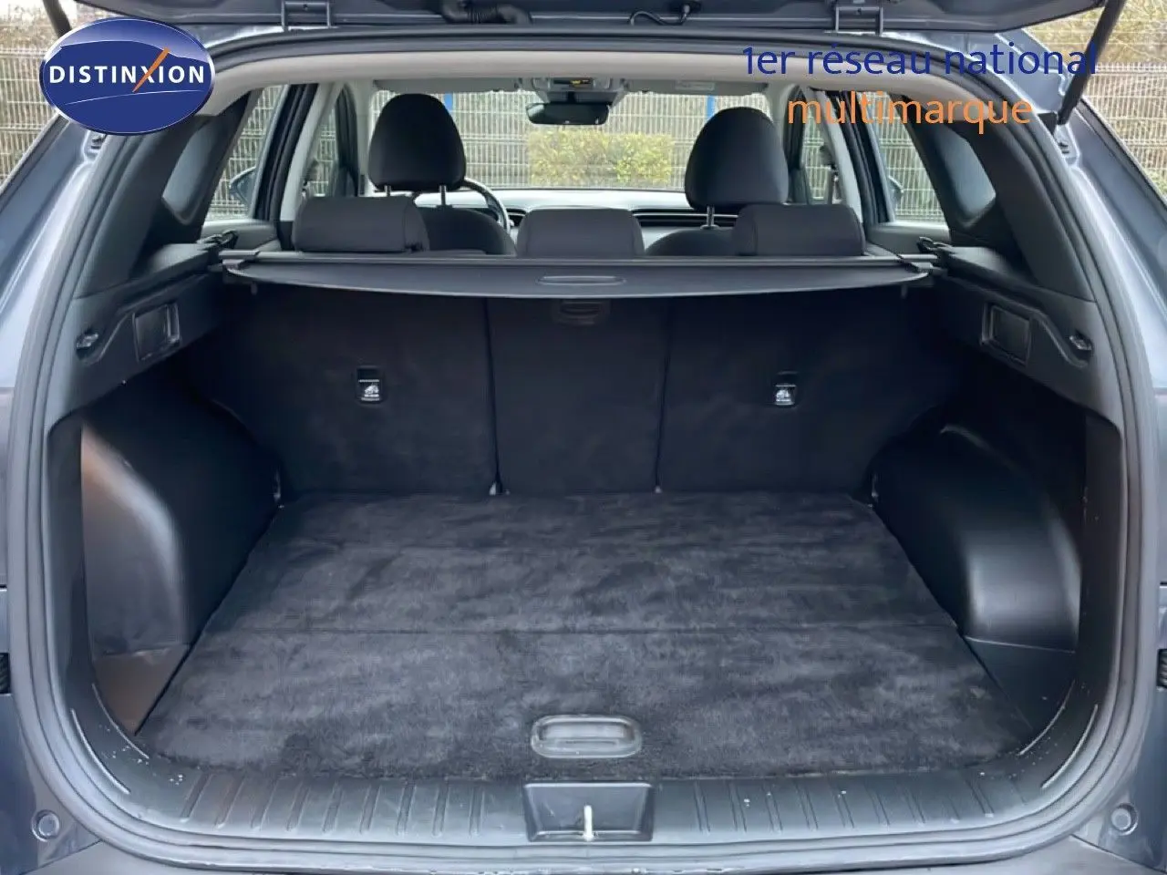 Coffre ouvert vu de l'arrière d'un Hyundai Tucson 2023 Dark Knight Metal, intérieur noir avec cache-bagages déployé.