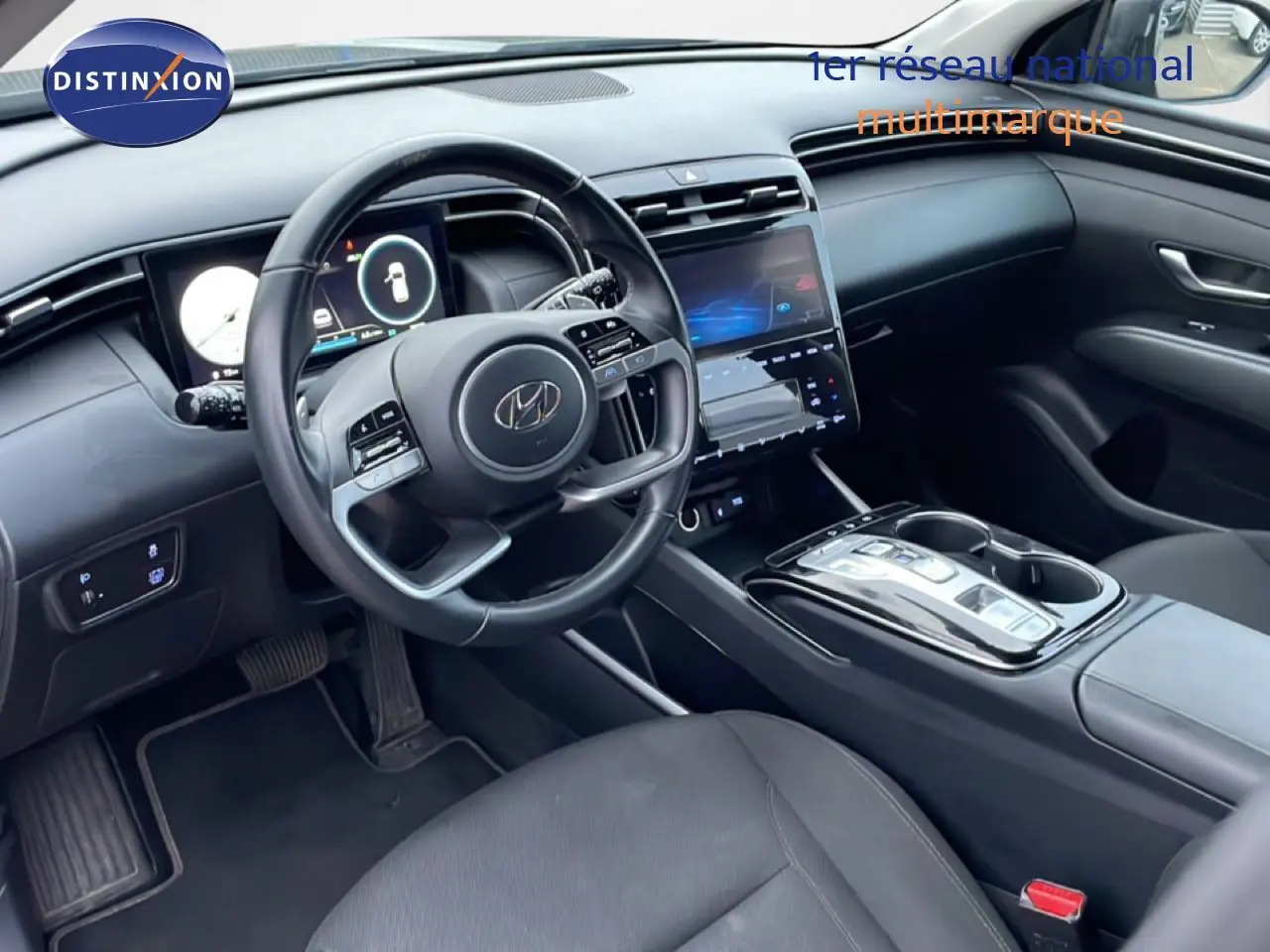 Vue intérieure côté conducteur du Hyundai Tucson 2023 avec tableau de bord numérique et console centrale tactile noire.