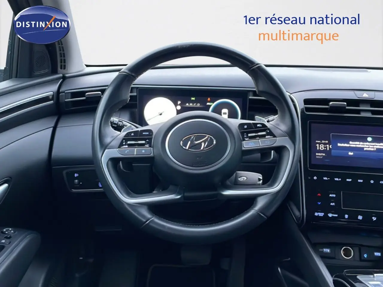 Vue intérieure centrée sur le volant cuir noir du Hyundai Tucson 2023 avec tableau de bord digital et écran tactile.