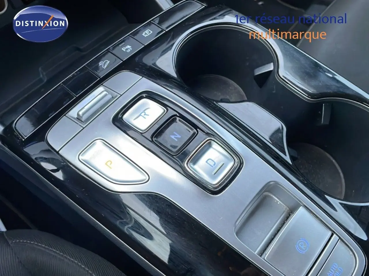 Gros plan sur la console centrale du Hyundai Tucson 2023, montrant les boutons de la boîte automatique et les porte-gobelets.