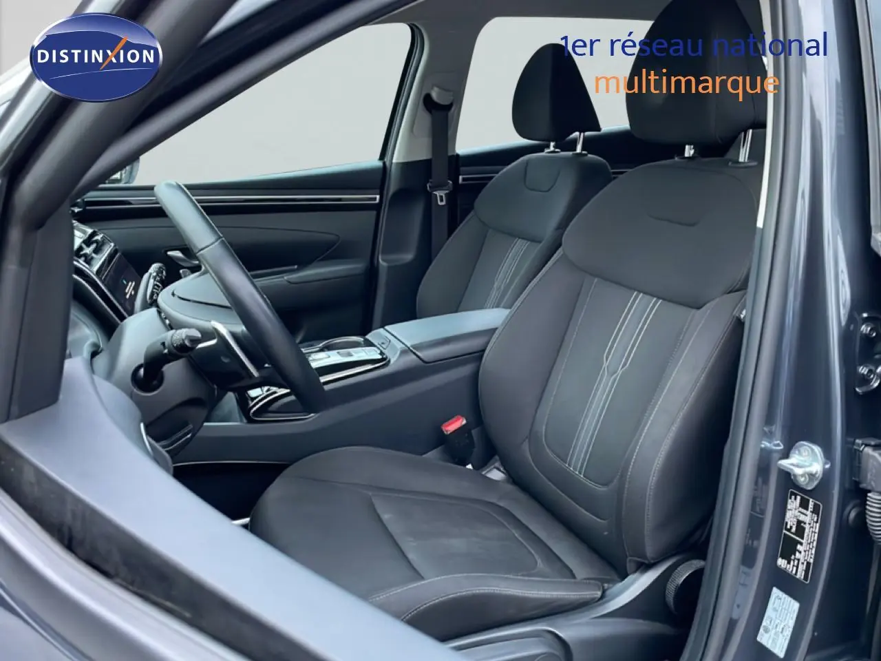 Vue intérieure côté conducteur du Hyundai Tucson 2023 en Dark Knight Metal, sièges tissu noir et volant multifonction.