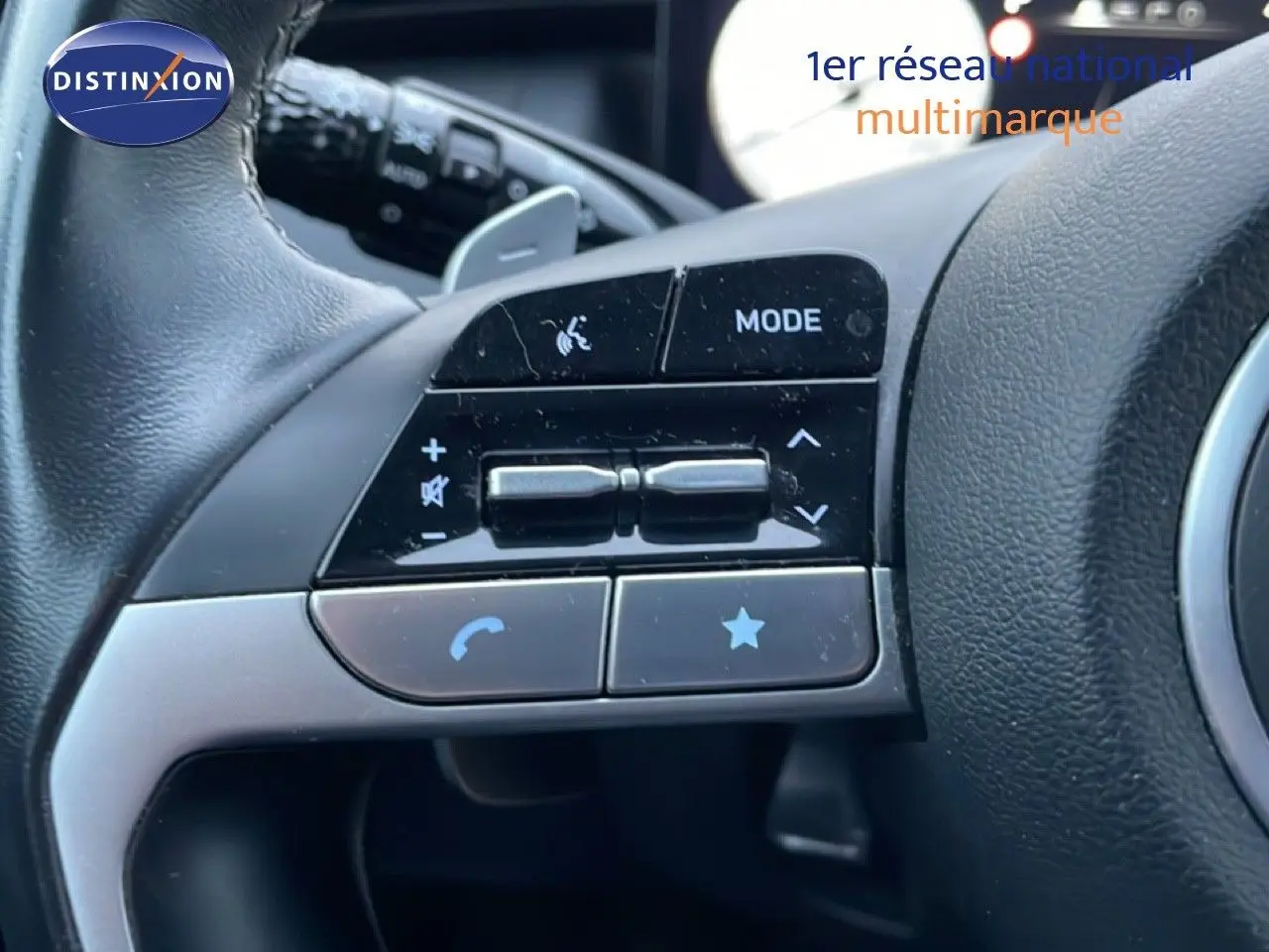 Gros plan sur les commandes gauche au volant du Hyundai Tucson 2023 en cuir noir, boutons de volume et mode visibles.