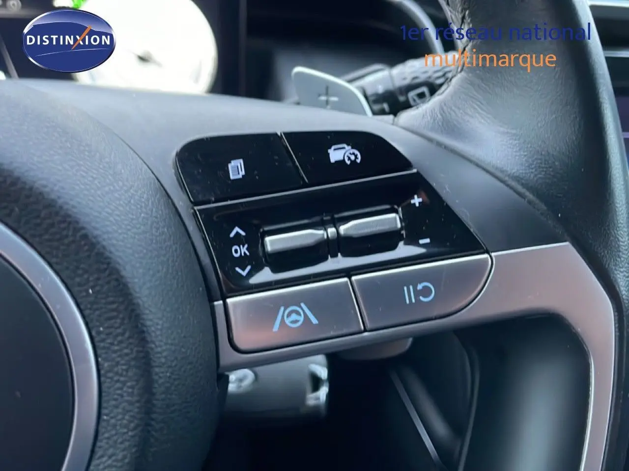 Gros plan sur les commandes au volant noir du Hyundai Tucson 2023, avec boutons de régulateur de vitesse et assistance au maintien de voie.
