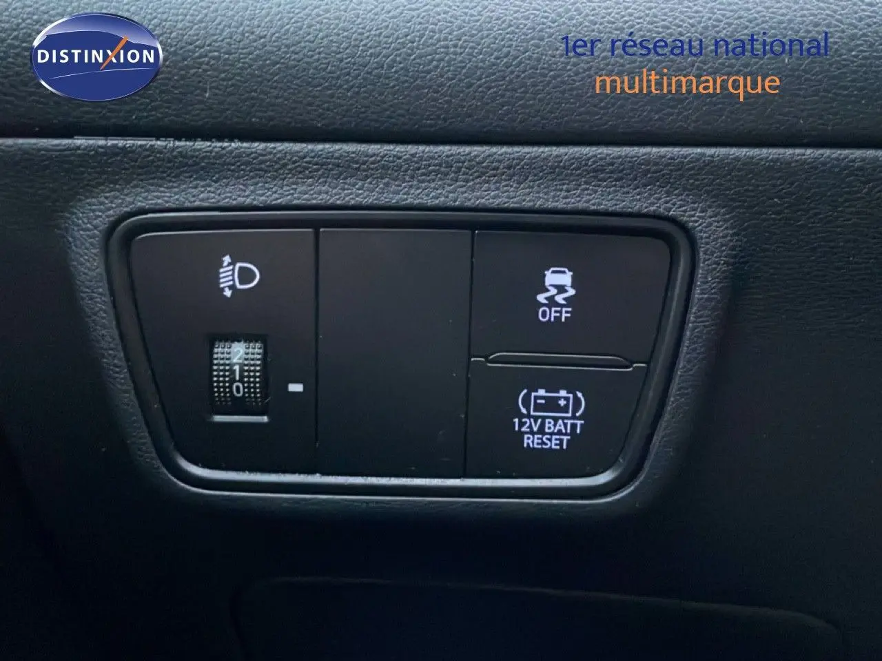 Gros plan sur les commandes intérieures noires du Hyundai Tucson 2023, avec réglage des phares et bouton de traction.