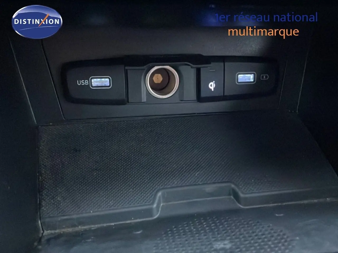 Vue rapprochée de la console centrale du Hyundai Tucson 2023, montrant les ports USB et prise 12V sur fond noir.