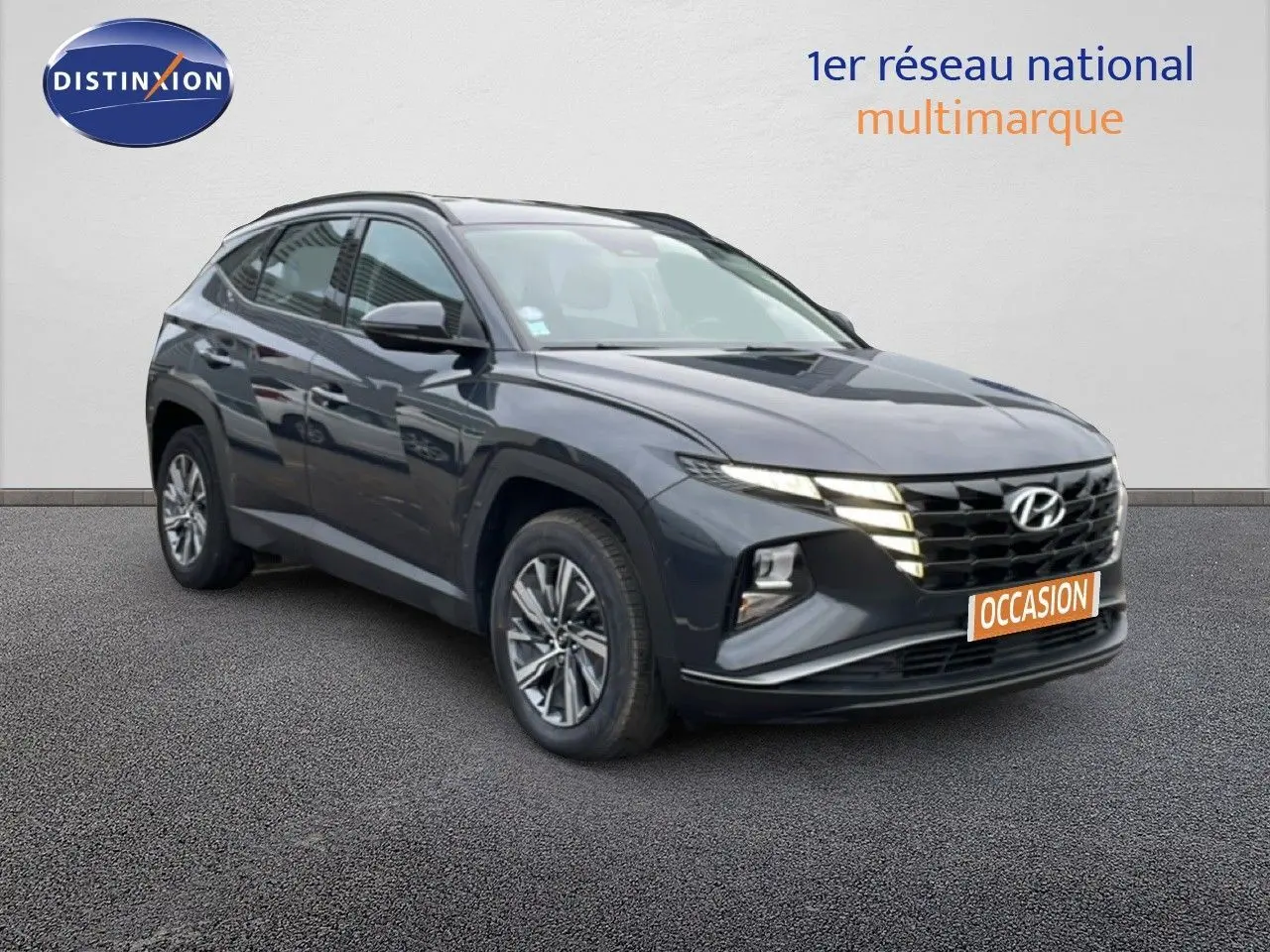 Hyundai Tucson 2023 hybride en Dark Knight Metal, vue 3/4 avant droite avec calandre et phares allumés.