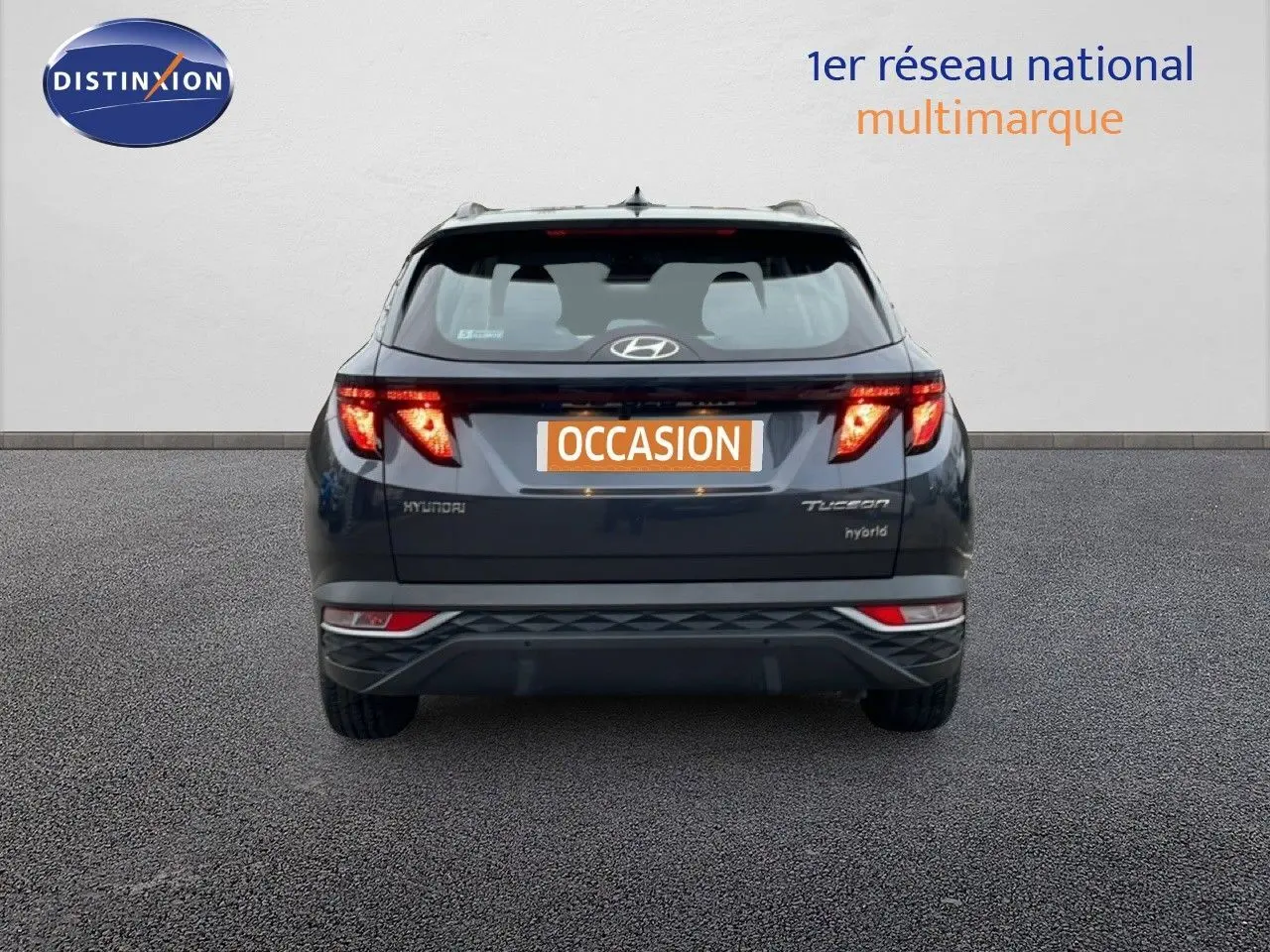 Vue arrière d'un Hyundai Tucson hybride 2023 en Dark Knight Metal avec feux LED allumés sur fond neutre.