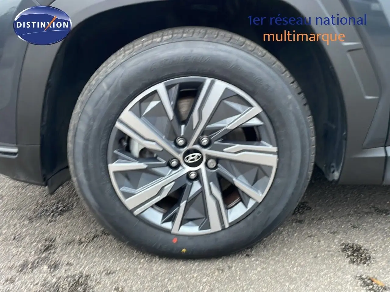 Gros plan sur la roue avant gauche du Hyundai Tucson 2023 Dark Knight Metal avec jante alliage bicolore.