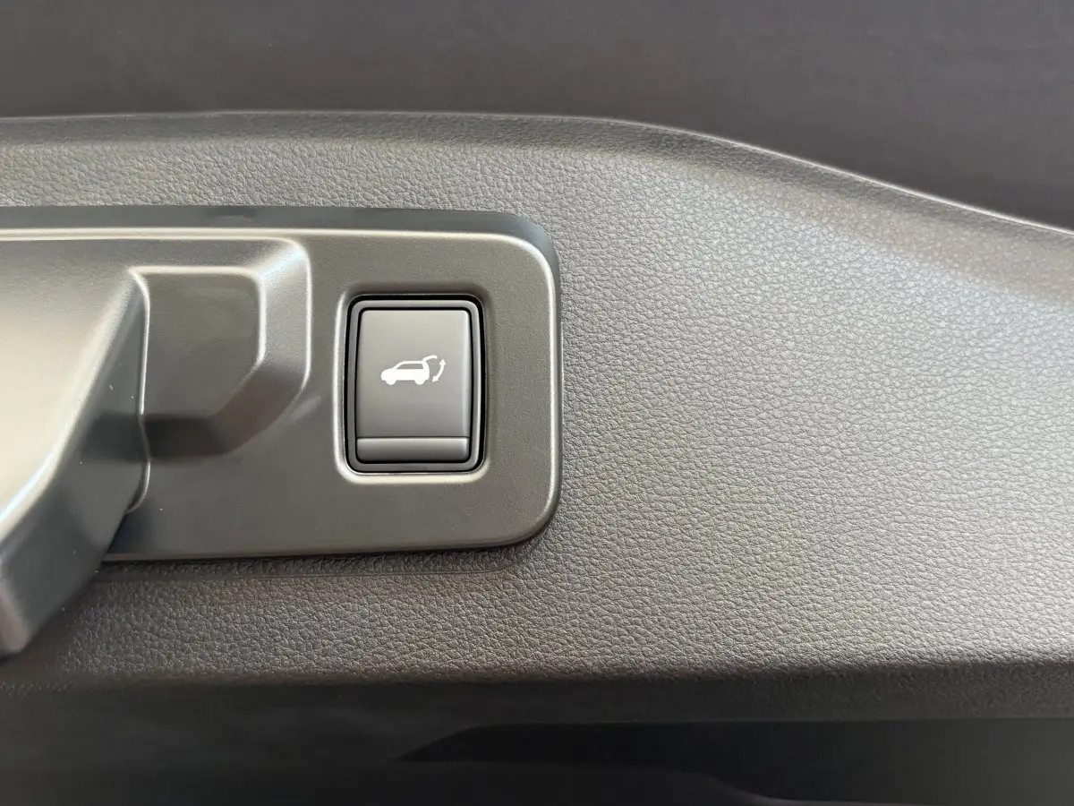 Gros plan sur le bouton d'ouverture électrique du coffre dans l'habitacle du Renault Espace blanc 2025.