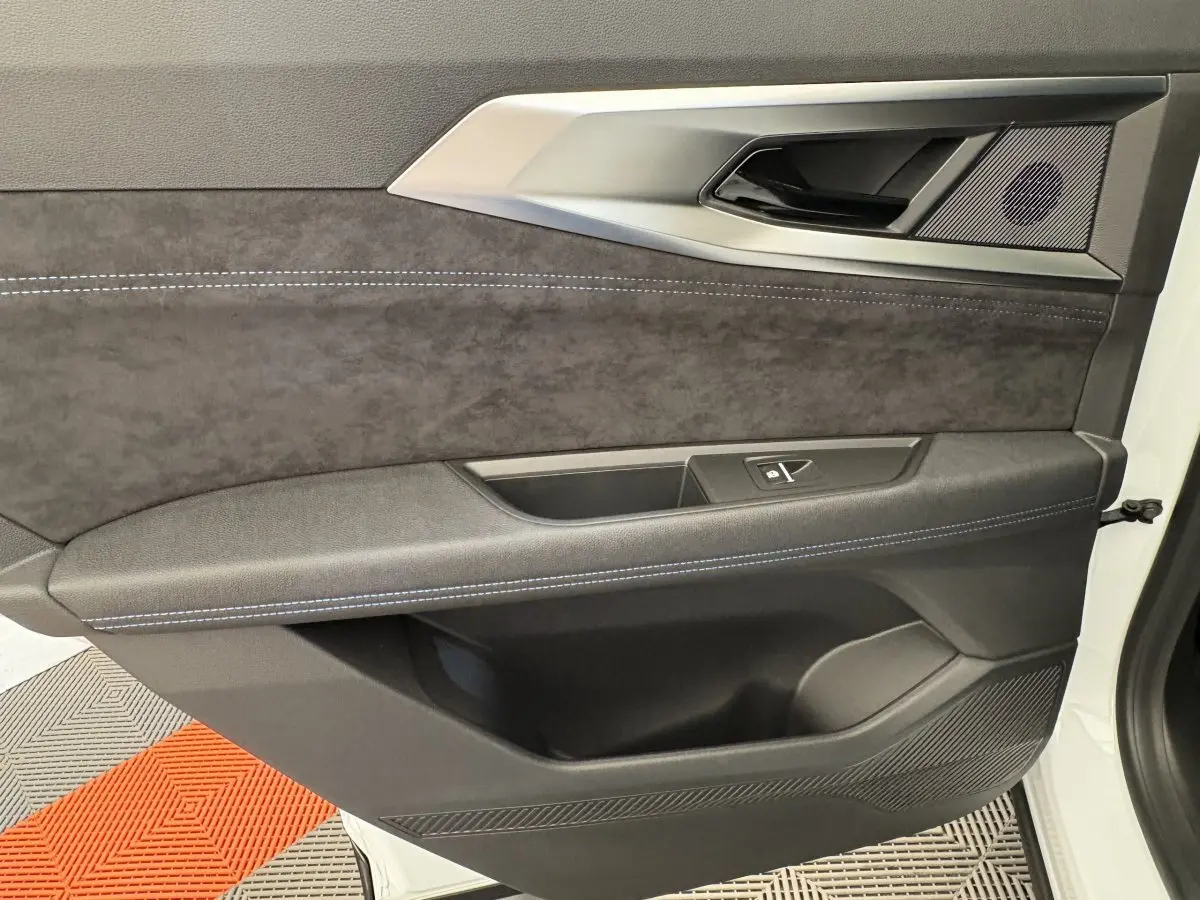 Vue rapprochée de la porte avant gauche du Renault Espace blanc, intérieur noir avec surpiqûres bleues et insert tissu.