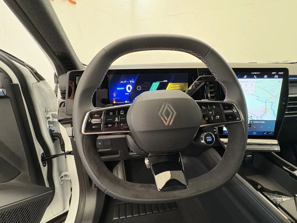 Vue intérieure centrée sur le volant en suède noir et les écrans digitaux du tableau de bord d’un Renault Espace blanc 2025.