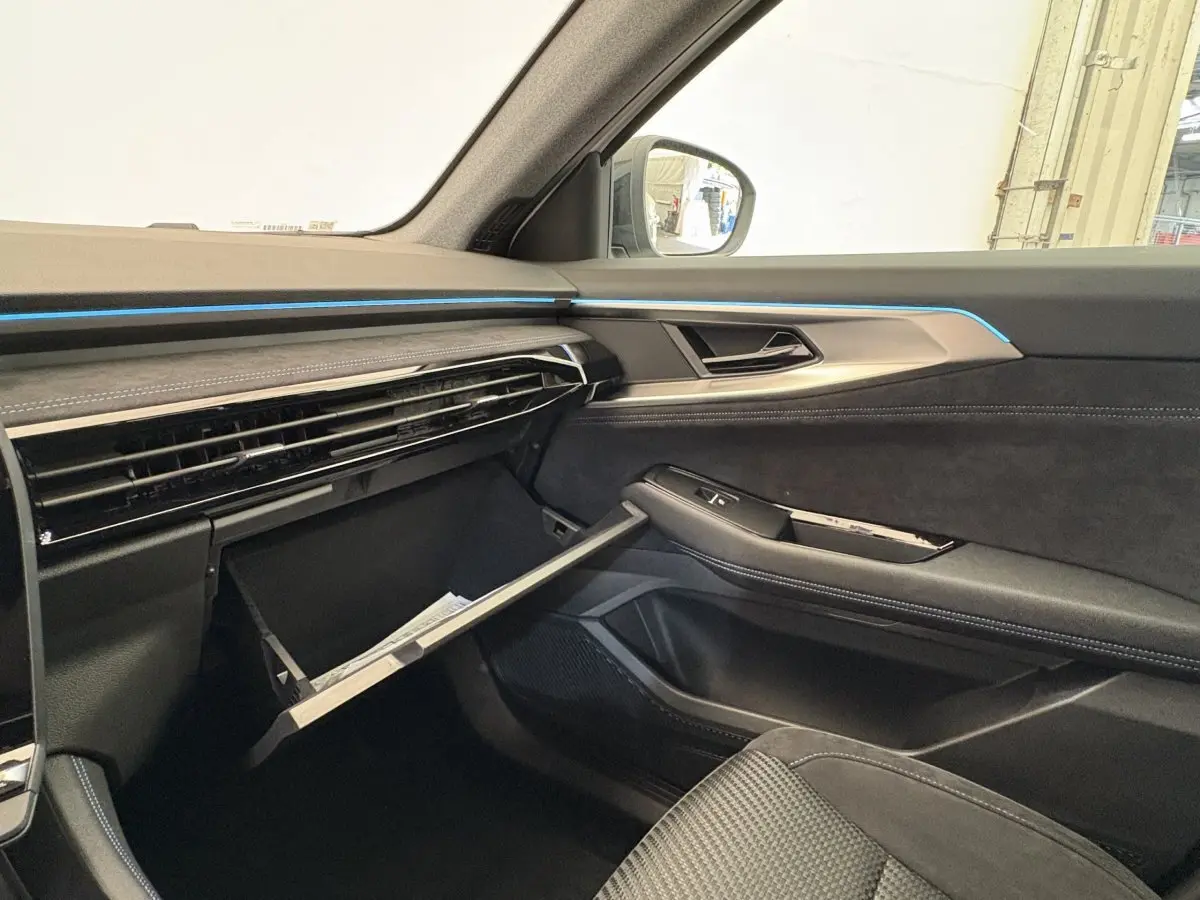 Intérieur côté passager du Renault Espace 2025 esprit Alpine, boîte à gants ouverte, finition noire avec éclairage bleu.