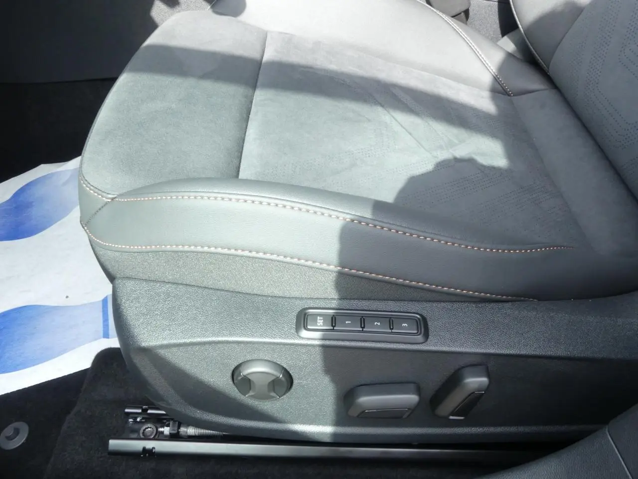 Gros plan sur le siège conducteur gris suédine avec surpiqûres cuivrées et commandes électriques mémoire du Cupra Formentor 2025.