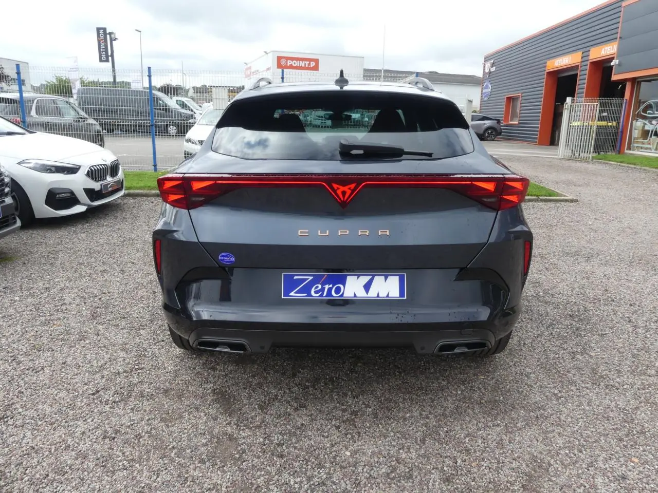 Vue arrière du CUPRA Formentor gris magnétique avec feux arrière en bandeau lumineux et double sortie d'échappement.