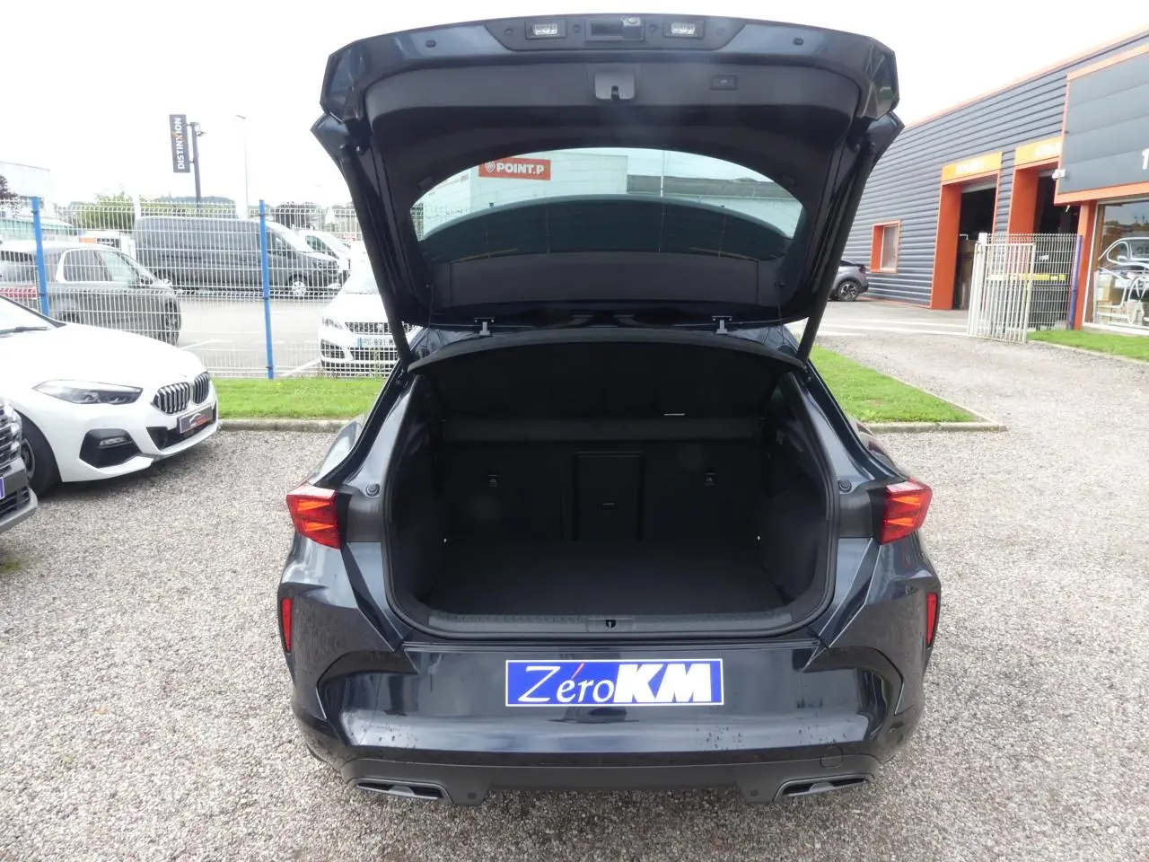 Vue arrière ouverte du coffre du CUPRA Formentor gris magnétique 2025, avec feux arrière LED et double sortie d’échappement noire.