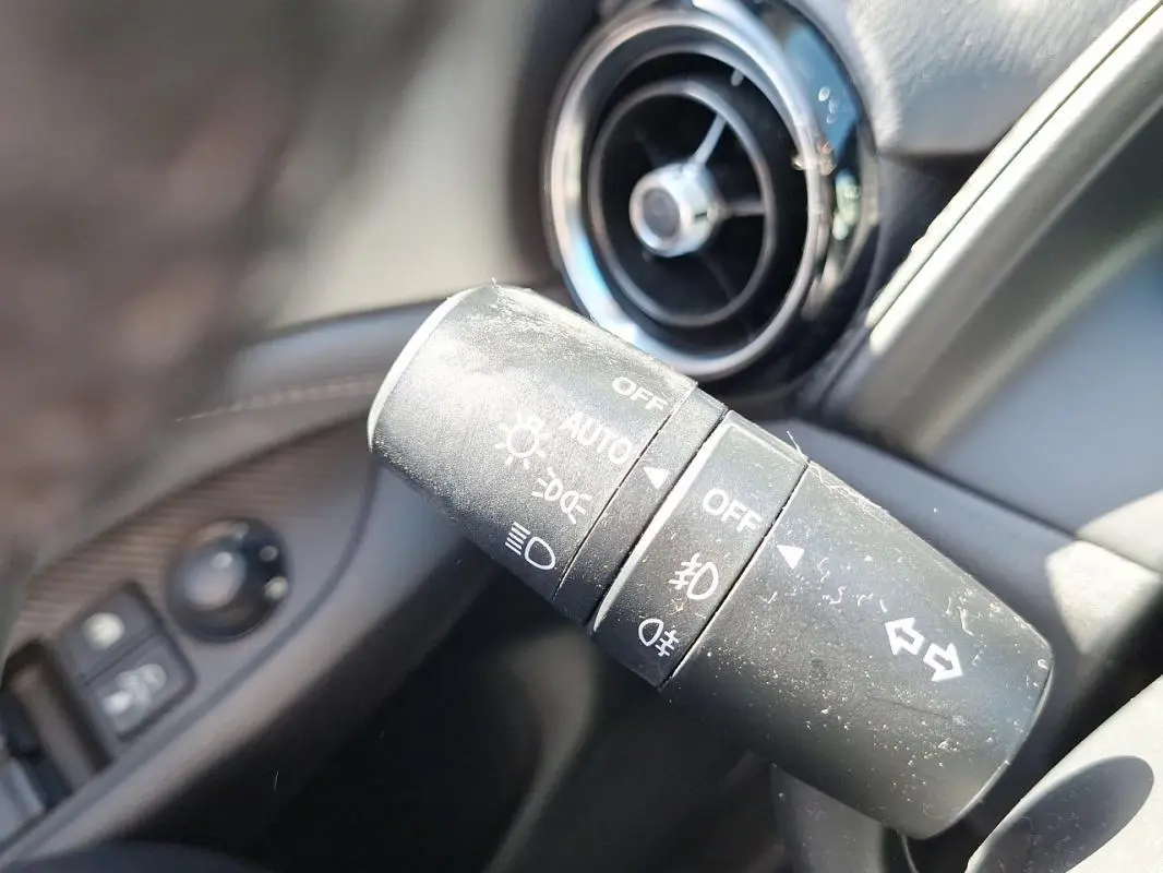 Gros plan sur la commande des phares et clignotants du Mazda CX-3 2021, avec aérateur circulaire en arrière-plan.