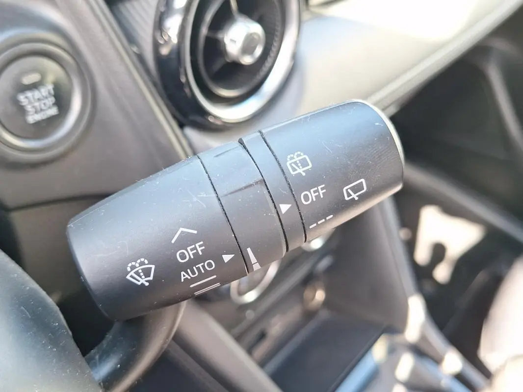 Gros plan sur la commande des essuie-glaces du Mazda CX-3 2021, avec bouton start/stop visible en arrière-plan.