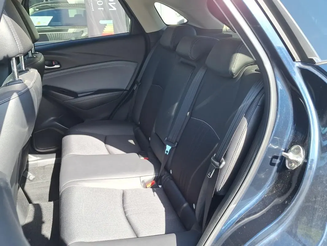 Vue intérieure côté droit des sièges arrière noirs du Mazda CX-3 bleu 2021 avec ceintures de sécurité visibles.