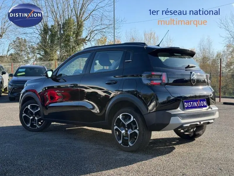 Vue 3/4 arrière droite d'une Citroën C3 1.2 Turbo 100ch PLUS noire Perla Nera avec jantes distinctives et toit noir.