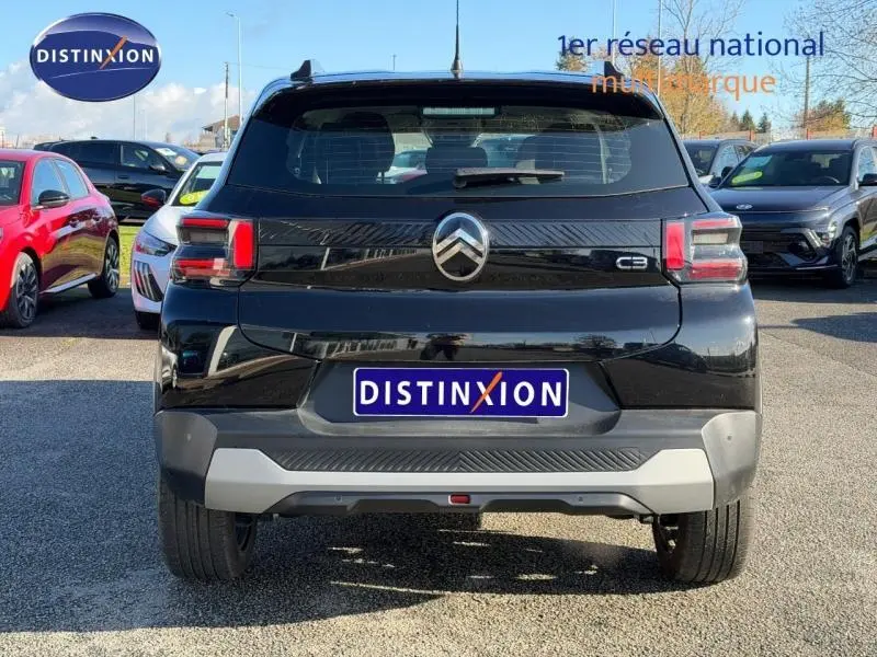 Vue arrière d'une Citroën C3 1.2 Turbo 100ch PLUS noire, avec logo et feux arrière distinctifs, sur parking extérieur.