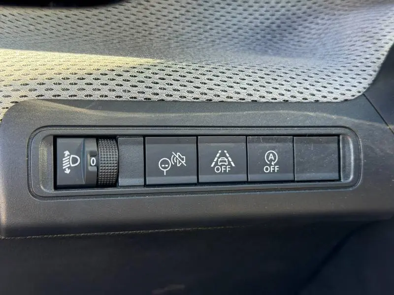 Gros plan sur les commandes de réglage des phares et aides à la conduite dans une Citroën C3 Noir Perla Nera 2025.