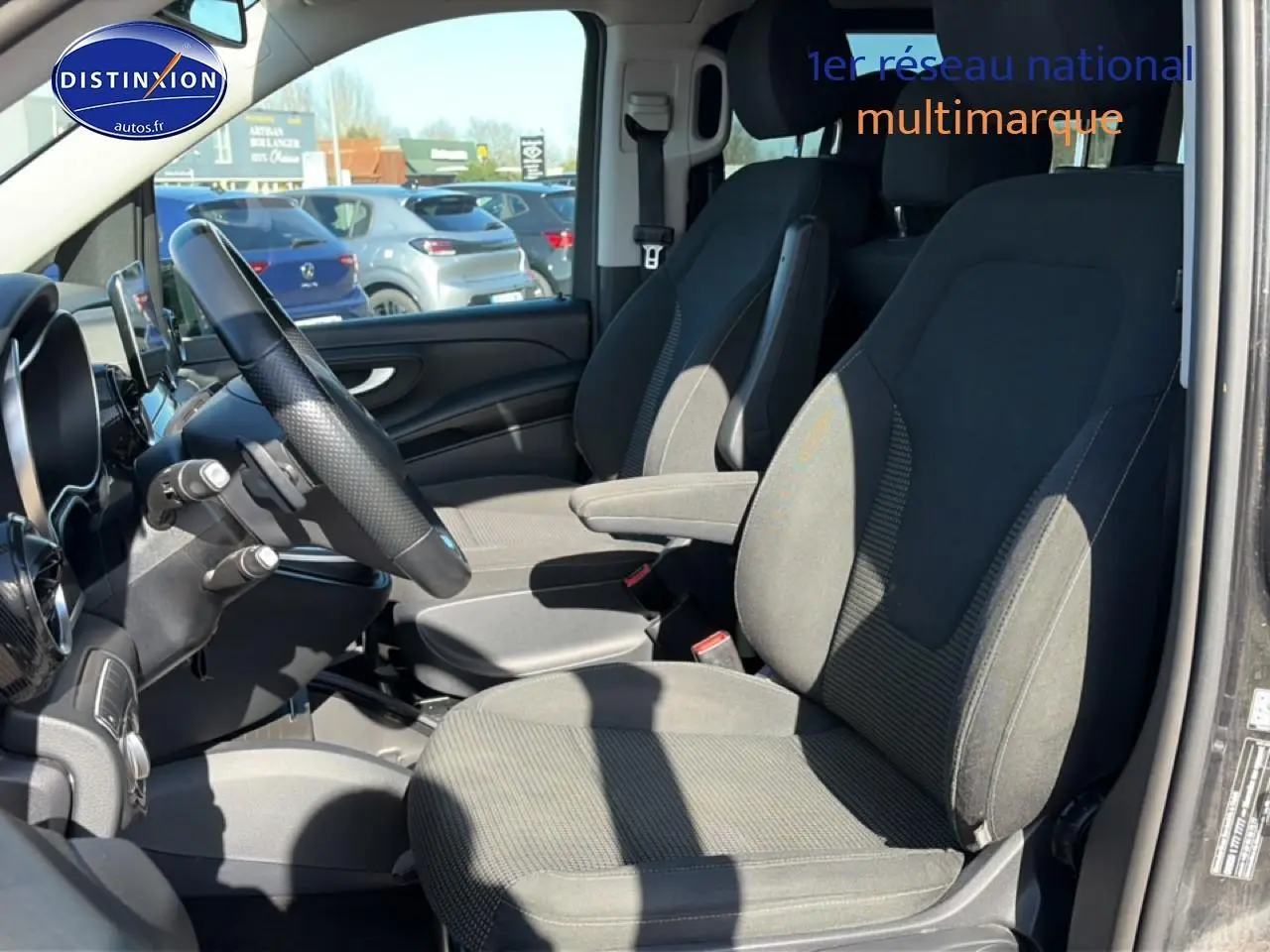 Vue intérieure côté conducteur du Mercedes Classe V 220 d long noir, sièges tissu Santos noirs et volant multifonction.