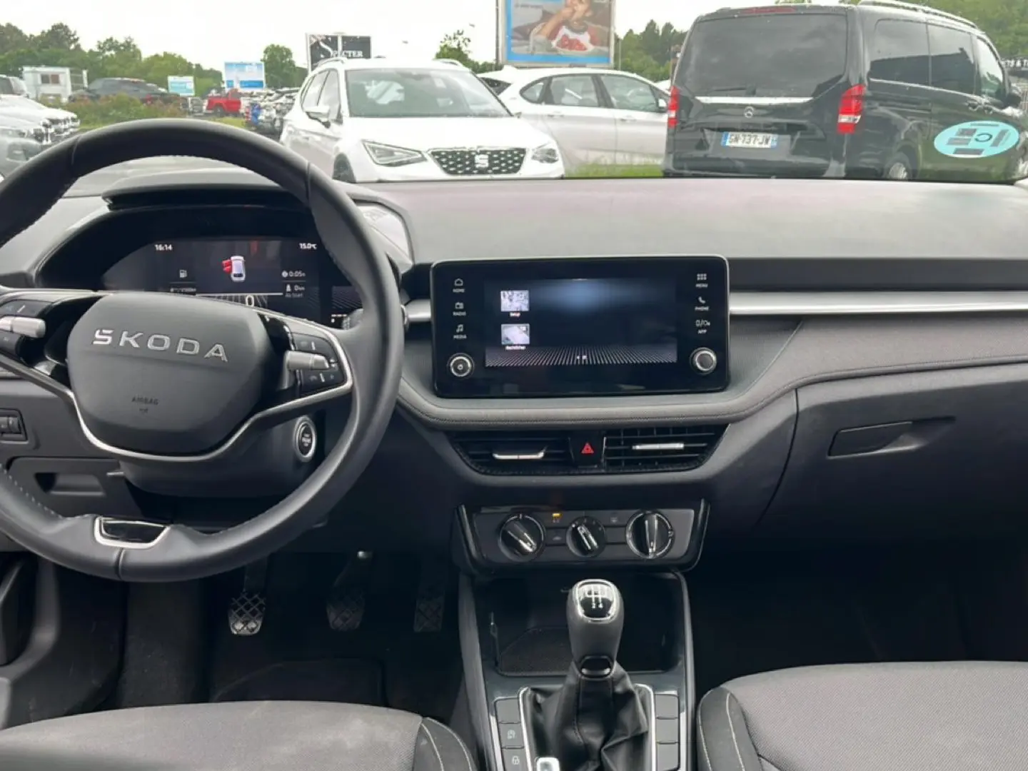 Vue intérieure de face du tableau de bord et volant cuir noir d'une Skoda Fabia 2025 avec écran tactile et levier de vitesses manuel.