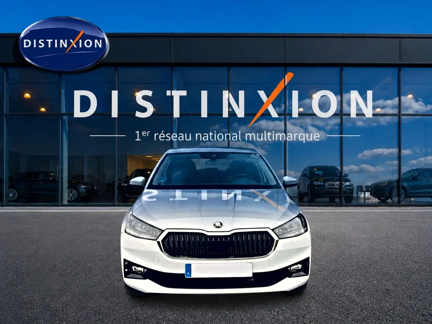 Vue frontale d'une Skoda Fabia blanche 2025 garée devant une vitrine avec logo Distinxion.