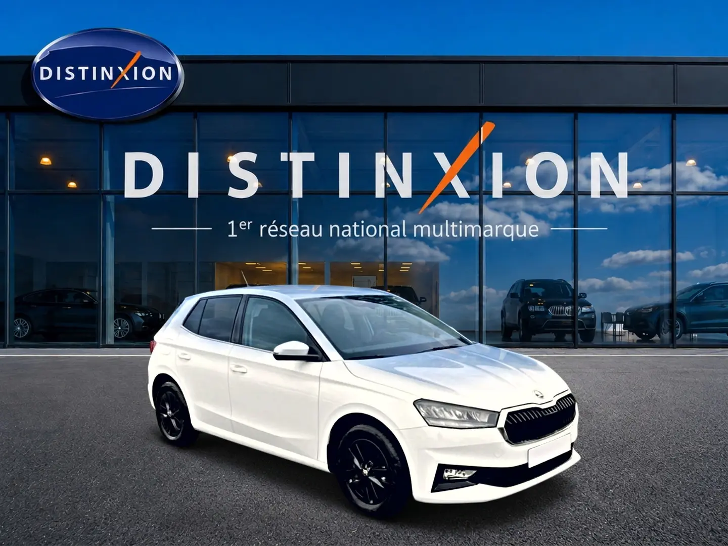 Skoda Fabia blanche vue en 3/4 avant droit, avec jantes noires et calandre distinctive devant showroom Distinxion.