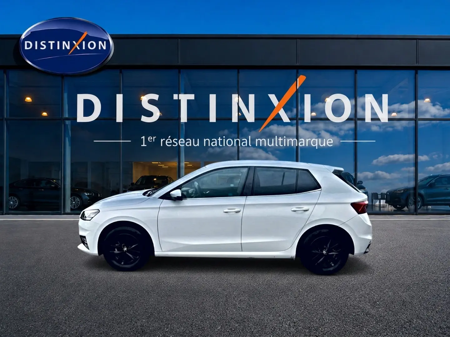 Skoda Fabia blanche vue de profil côté gauche, jantes alu noires, devant vitrine Distinxion.