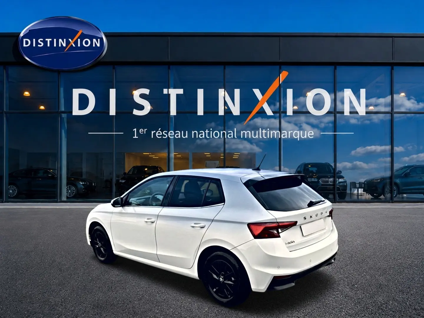 Vue 3/4 arrière droite d'une Skoda Fabia blanche 2025 avec jantes noires, garée devant une vitrine Distinxion.